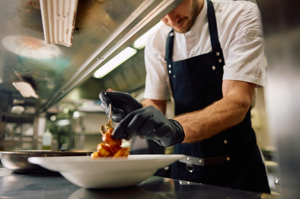 Chef en pleine préparation d’assiette – illustration du travail minutieux dans la restauration de proximité.