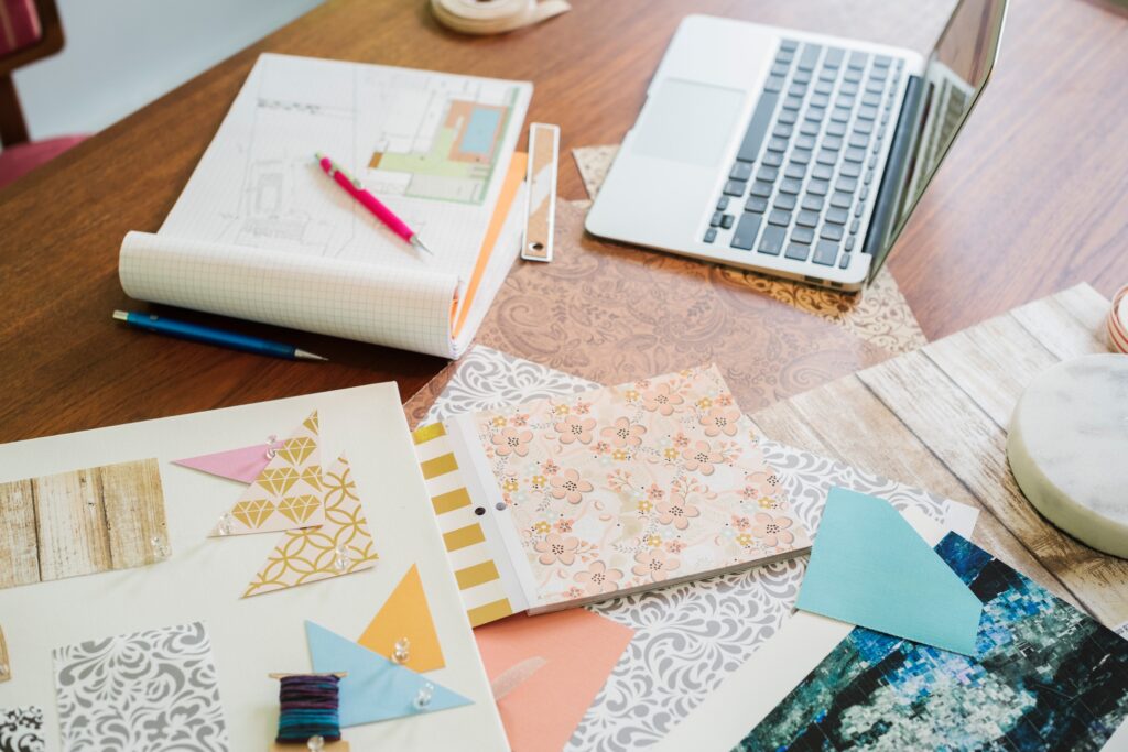 Photo représentant le matériel d’un artisan créatif en Ardèche – tissus, carnets, motifs et tablette graphique.